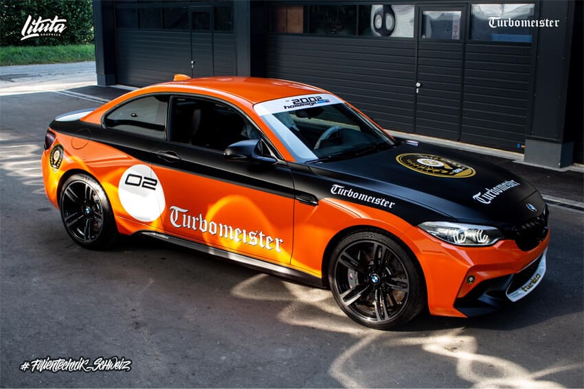 Orangefarbener Sportwagen mit schwarzen Streifen, parkend.
